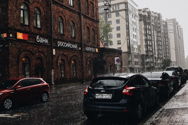 A rainy urban scene with wet streets and parked cars in Saint Petersburg, Russia, capturing the city's architecture.